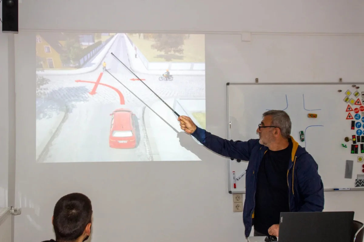 Fahrlehrer Suat Dastemir erklärt im Theorieunterricht eine Vorfahrtsituation am Beamer